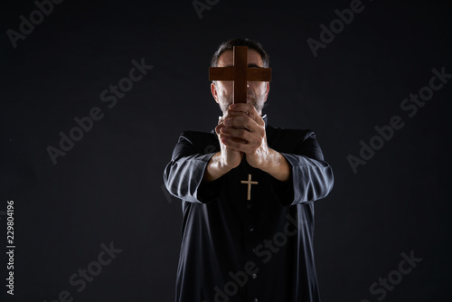 Priest holding cross of wood praying
