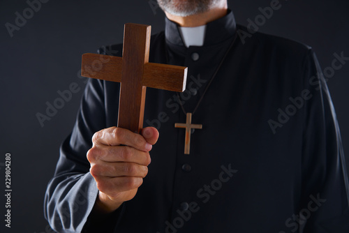 Priest holding cross of wood praying