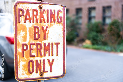 Parking by permit only street traffic sign outside, outdoors with car parked behind on street, violation