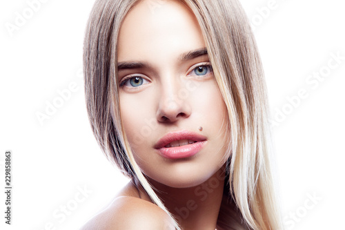 Close-up beauty model girl face looking at camera. Natural lips, nude make-up, healthy clean skin, blond hair, blue eyes. White background. Copy space