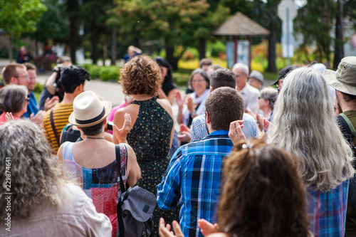 100 People applauding to a public speech given outdoors in the village - Shot from the back during an alternative political gathering