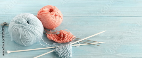 Knitting wool and knitting needles in pastel blue and pink colors on blue wooden background. top view.copy space.banner