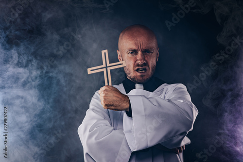 Catholic priest exorcist in white surplice and black shirt