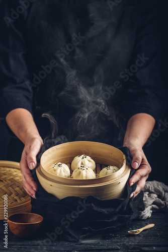 Woman presenting dim sum dumplings in steamer