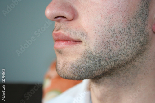 A man's face with a slight beard. A few days beard on the guy's chin. Macro picture taken from the profile.