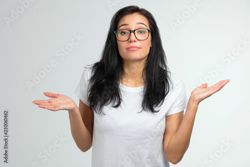 close up portrait of a pretty woman in glasses shrugging shoulders isolated on a white background. I don't know. indifference concept