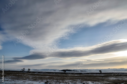 Frozen Lake Baikal. Beautiful stratus clouds over the ice surface on a frosty day.