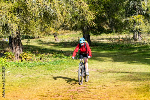 Mountainbiker fährt über grüne Wiese durch Wald