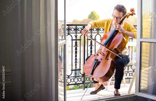 Female classical musician playing cello on the terrace