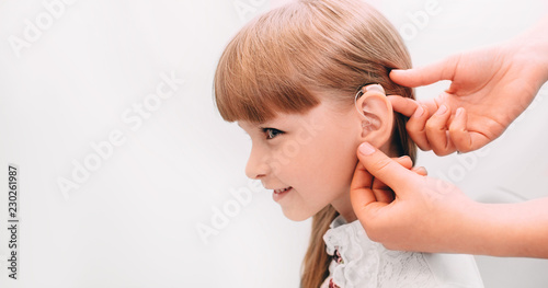 Doctor putting an hearing aid in a child's ear