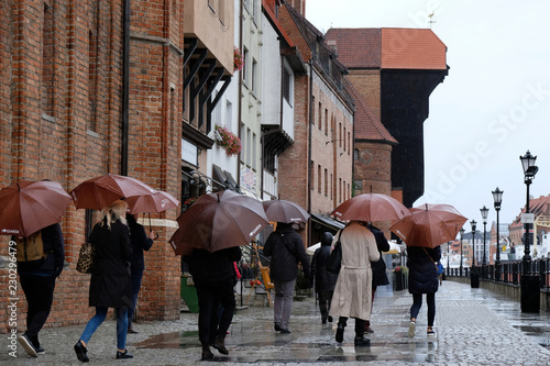 Polska, Gdańsk - turyści z brązowym parasolami zwiedzający miasto w deszczową pogodę