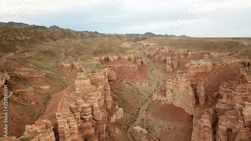 Charyn canyon. Grand canyon. Red sand and rocks. The sky in the clouds. Steep cliffs of the canyon. Shooting with the drone. Unusual footage. Clay rock canyon. Earth layers and different colors of roc