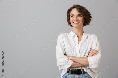 Happy young business woman posing isolated over grey wall background.