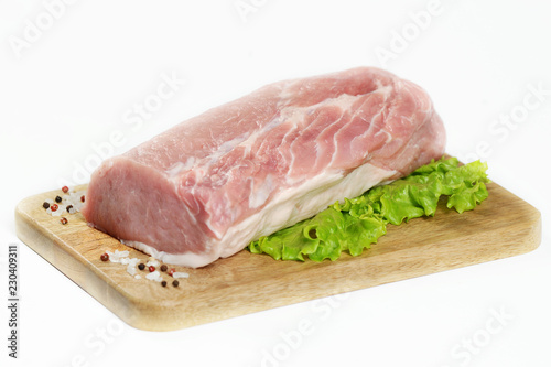 A piece of raw meat on a wooden board. A piece of pork carbonate for steaks. White background. Close-up. 