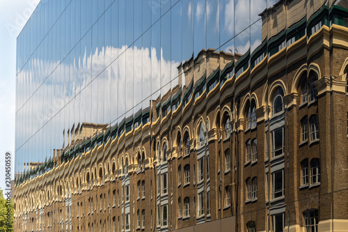 Old brick building reflected in windows of modern glass facade, new versus old concept