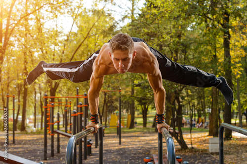 Athletic guy doing gymnastics outdoor