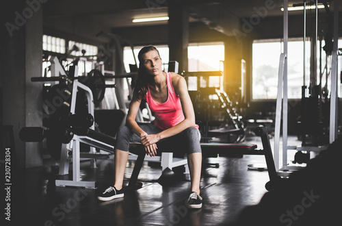 Fit woman sitting and relax after the training session in gym,Concept healthy and lifestyle,Female taking a break after exercise and workout