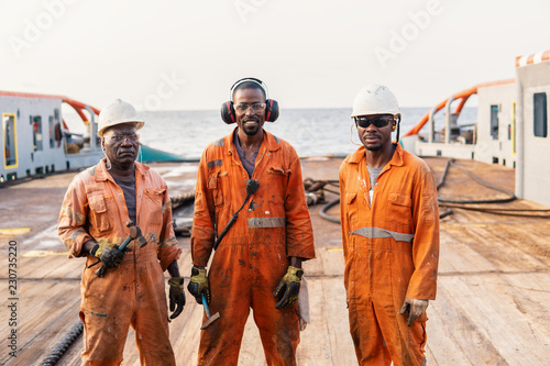 Seamen crew AB or Bosun on deck of offshore vessel or ship , wearing PPE personal protective equipment - helmet, coverall, lifejacket, goggles. Towing team