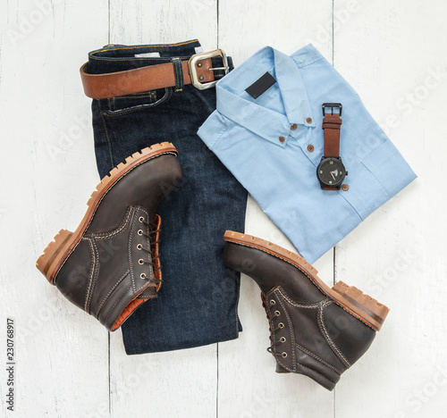 Men's casual outfits for man clothing set with blue shirt, blue jeans, belt, watch and ankle boot isolated on white wooden background, Top view