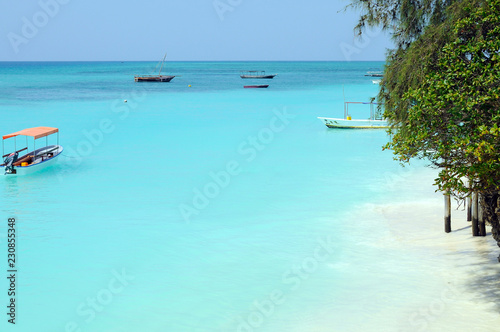 Crystal clear waters at Zanzibar beach. Safety boat on the paradise water before storm arriving