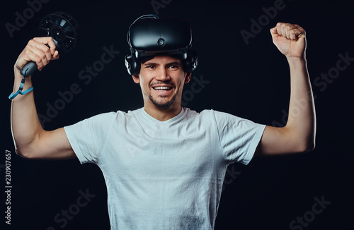 Pro player rejoices in his victory in the competition, wearing virtual reality glasses and holds joysticks.