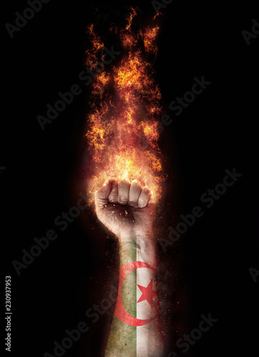Algeria flag in a hand which is on a fire