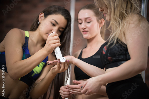 Three young woman lubricates dancers hands with cream