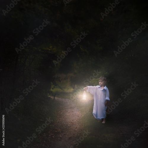 Surreal scene with small boy walking in night with lantern