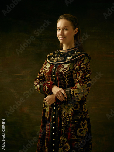 Girl standing in Russian traditional costume. Woman is wearing in old retro boyary outfit at darl studio