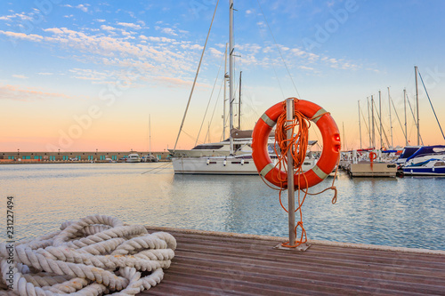 the quay of a marina at the sunset /a mooring rope with a lifebelt on the quay of a marina at the sunset