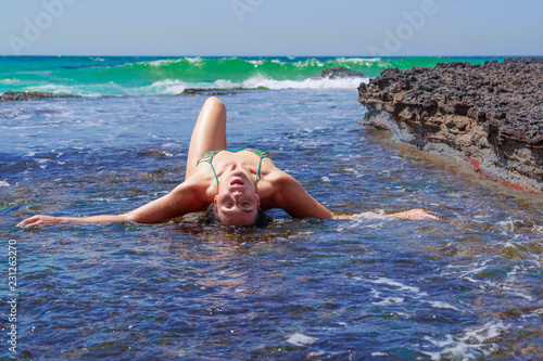 Woman reclining on surf covered rock shelf eros nature
