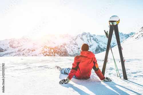 Narciarz sportowiec siedzi w górach Alpy w słoneczny dzień - dorosły mężczyzna, ciesząc się zachodem słońca z biegami nieba obok niego - koncepcja sportów zimowych i wakacji
