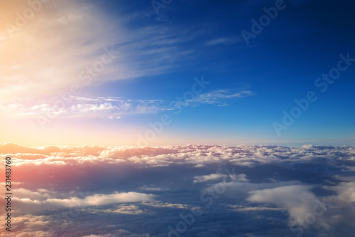 sunset with bright sun rays over cumulus clouds view from the window of an airplane