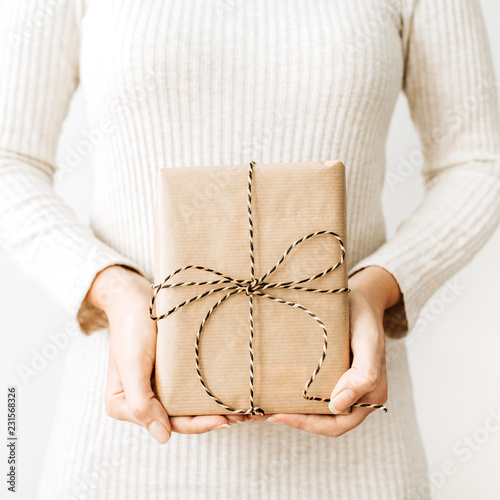 Young woman with craft gift box on white background. Christmas / New Year / Winter festive composition.