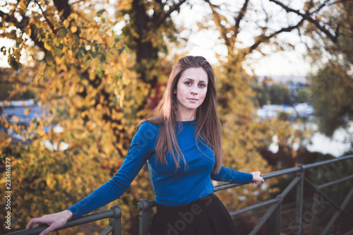 Girl in a blue long sleeve shirt and a skirt on a street. Autumn time.