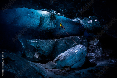 Ice climber abseiling into massive cavern in ice cave