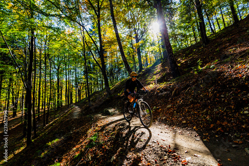 Cycling woman riding on bike in summer mountains forest landscape. Woman cycling MTB flow trail track. Outdoor sport activity.