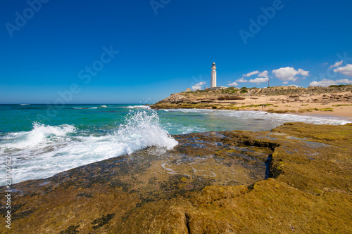 ocean wave breaking on coast rock next to Trafalgar lighthouse