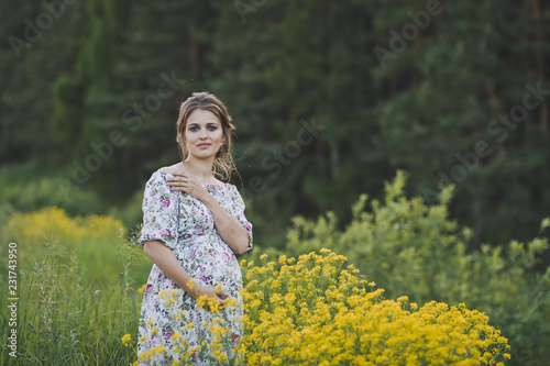 A beautiful girl in a long light dress in a clearing with yellow flowers 1707