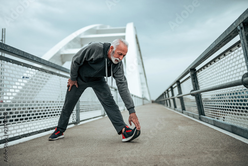 Senior athlete stretching outdoors in the city.