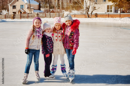Four little happy girls are skating. They have fun with friends.
