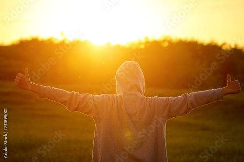 a man in the light of the sunset with his hands up, the concept of success, freedom and joy