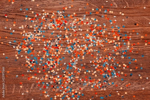 Confetti. The background of the wooden surface coating is red-brown.