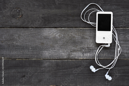 White music player with headphones on a dark wooden background