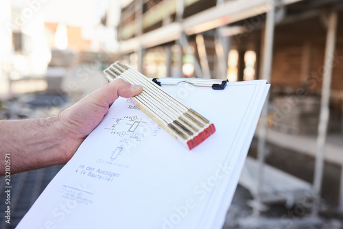 Zollstab mit Klemmbrett in der Hand, auf Baustelle zeigen