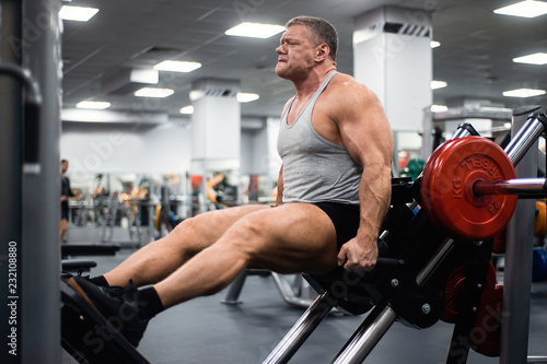 muscular man trains his legs in the gym. Health and fitness concept
