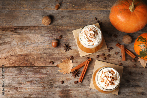 Flat lay composition with glasses of tasty pumpkin spice latte and space for text on wooden background