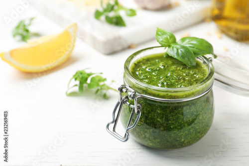 Homemade basil pesto sauce in glass jar on table