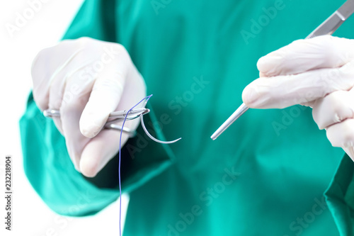 Doctor holding surgical forceps suture needle, suturing material