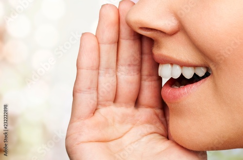 Close up portrait of a smiling skin care woman whispers (tells